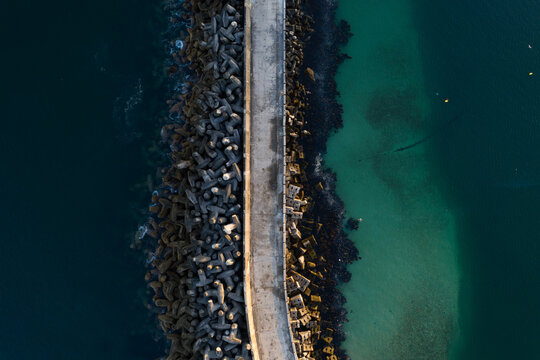 Aerial view of a breakwater surrounded by turquoise waters in Gansbaai, South Africa