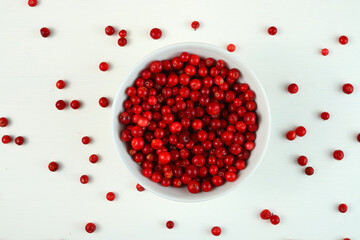 Bright red lingonberries in a large bowl on a white background.