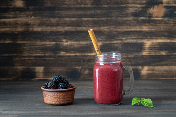 Fresh blackberry smoothie in the glass jar on wood background, close up