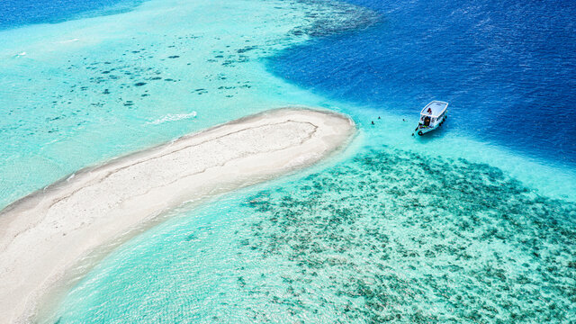 Aerial view of a sandbank, North Maldives Atoll, Maldives, Indian Ocean with an anchored Dhoni, boat and people swimming