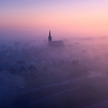 Aerial view of  the village of Schermerhorn in the mist, with it's church, houses, canals en farmer's land, municipality of Alkmaar, North Holland, Netherlands