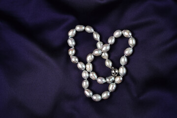 Pearl necklace on a background of beautiful satin purple fabric.