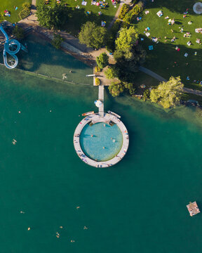 Aerial view of an outdoor public pool that looks like the search logo. a slide in the shape of the g of google and some swimmer in Z√ºrich Switzerland