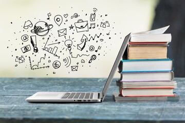 Stack of books with modern laptop on table
