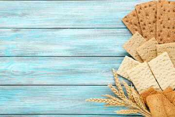 Tasty crispbread with wheat ears on blue wooden table