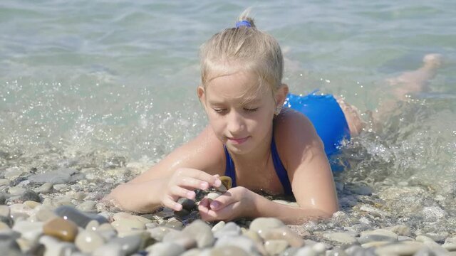Cute child girl bathes in sea. Family vacation concept.