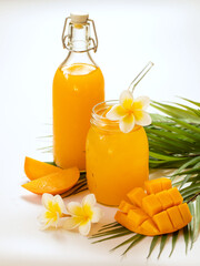 Fresh mango juice in the jar and bottle on the white background. Tropical fruit concept.