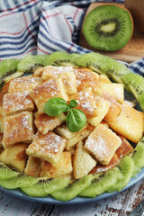 Austrian dessert Kaiserschmarrn served with sugar powder and kiwi fruit