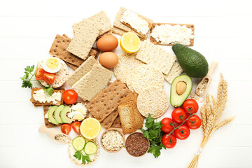 Crispbread with cream cheese, eggs and vegetables on white wooden table