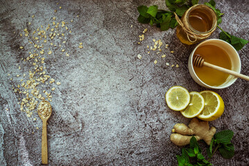 honey, lemon, mint, ginger, oatmeal with a spoon - home remedy to prevent colds on a gray background