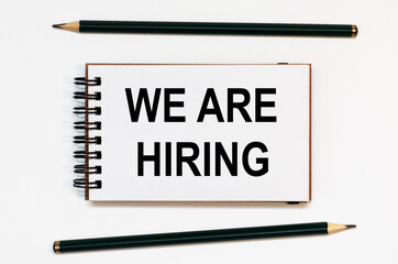 WHITE SPIRAL NOTEBOOK, TWO PENCILS WITH TEXT WE ARE HIRING