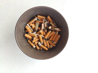 Ashtray full of cigarrettes in white background.