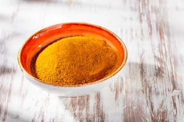 turmeric powder in bowl on old wooden background