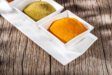 turmeric powder in bowl on old wooden background