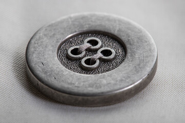 a metal button with a slotted swept loop on the flap of the raincoat sleeve made of beige fabric