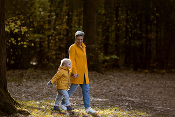 Obraz premium Young woman hugging her small son in the autumn park