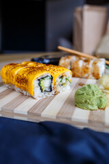 Set of traditional japanese food on a dark background. Sushi rolls, nigiri, raw salmon steak, rice, cream cheese, avocado, lime, pickled ginger. Asian food frame.