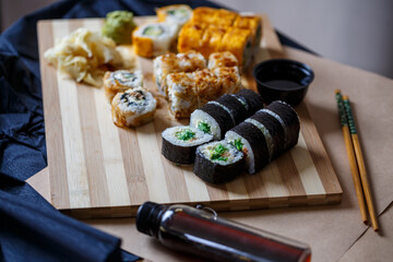 Sushi set with different types of rolls and sashimi made from eel, salmon, tuna, shrimp, red caviar and tobiko flying fish roe. Pan-Asian and Asian food and dishes on a black concrete kitchen table.