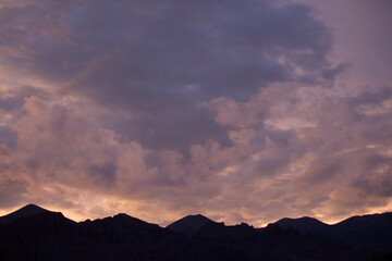 Enchanting sunset. View of the mountains silhouette at nightfall. Beautiful dusk colors in the sky and clouds. 
