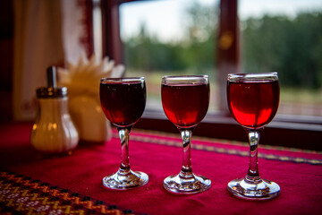 eyelets with red liqueur on the table with a red tablecloth against the background of the window