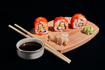 Sushi rolls and chopsticks on black background