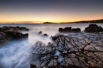 Sea shore with rocks at sunset. Seascape in summer time. Rocks and water. Long exposure. Mediterranean sea. Travel - image.