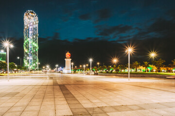 Batumi, Adjara, Georgia. Illuminated Alphabet Tower And Lighthouse At Promenade Near Miracle Park, Amusement City Park On Evening Or Night Sky Background. Blue Hour. Modern Urban Architecture