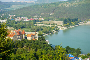 Naklejka na ściany i meble a beautiful castle immersed in the dense green vegetation of the mountains on the Abrau Durso lake on a clear summer day