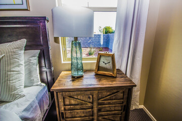 Lamp And Clock On Wooden Nightstand In Bedroom