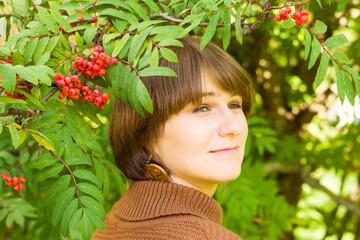 Naklejka premium beautiful woman with a branch of rowan in autumn in the park, close-up portrait