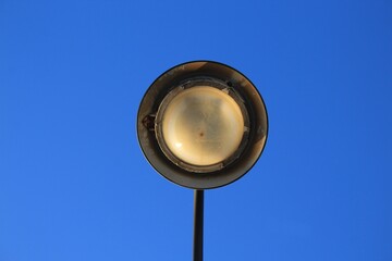 antique lamppost taken from the bottom upwards. Roundish concentric and symmetrical shape stands out against the celestial background