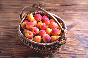 Natural ripe apricots in a wicker basket on a natural wooden background, close up