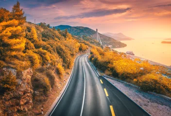 Photo sur Aluminium Le salon Vue aérienne de la route de montagne et de la belle forêt orange au coucher du soleil coloré en automne. Dubrovnik, Croatie. Vue de dessus de la route, des arbres, de la mer, de la montagne, du ciel rouge en automne. Paysage avec autoroute et côte maritim