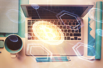Blockchain theme hologram drawings over computer on the desktop background. Top view. Multi...