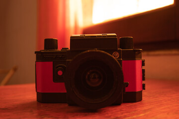 black and red plastic analog camera, on a piece of furniture