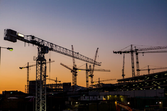 Cranes over construction site at sunset