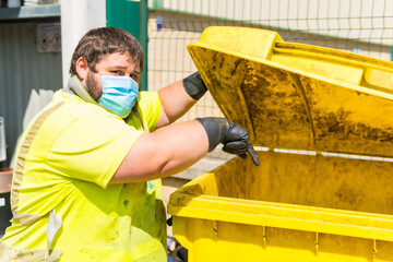 Worker in a recycling factory or clean point and garbage with a face mask and with security protections, new normal, coronavirus pandemic, covid-19. Operator cleaning and ordering the installation