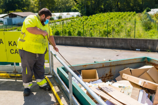 Worker in a recycling factory or clean point and garbage with a face mask and with security protections, new normal, coronavirus pandemic, covid-19. Ordering the carton container