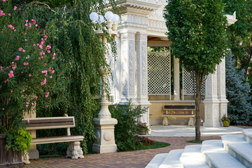 Fototapeta na wymiar beautiful bench in a city park with beautiful trees, flowers, shrubs and street lights on a summer day