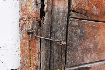 a fragment of an old wooden door made of boards covered with peeling and cracked green paint. The door has a handle, latch and door trim.