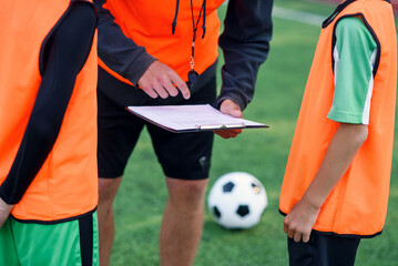 Professional soccer coach tells the strategy of football game to his attentive teen players at...