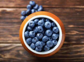 Pot of blueberries on an old wooden table. Selective focus.