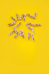 many wooden clothespins on a yellow background, as a substrate pin clothes peg