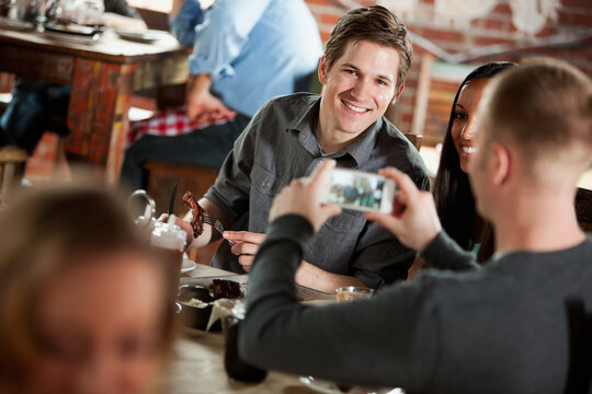 Barbeque: Man Takes Cell Phone Picture of Couple at Table