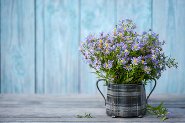 Symphyotrichum novi-belgii beautiful delicate flowers in an old vase in the open air in the garden on the table.