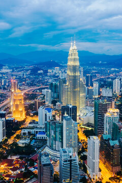 Asia, Malaysia, Selangor State, Kuala Lumpur, elevated view of iconic 88 storey steel-clad Petronas Towers and KL city centre skyline - illuminated at dusk