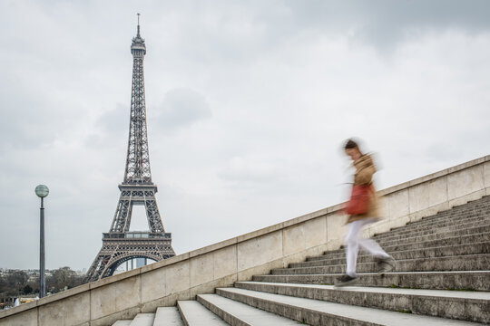 A woman walking down the stairs with the Eiffel Tower in the background