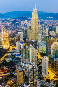 Asia, Malaysia, Selangor State, Kuala Lumpur, elevated view of iconic 88 storey steel-clad Petronas Towers and KL city centre skyline - illuminated at dusk