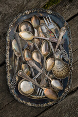 Antique spoons and utensils in a silver plate covered with patina on an old wooden background