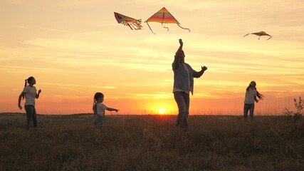 dad with children plays with kites at sunset in park. Outdoor family game. Daddy and healthy...